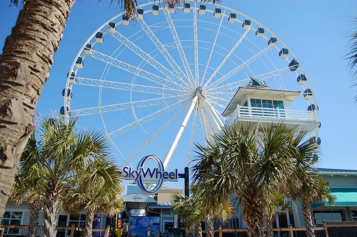 A dynamic exterior shot featuring the SkyWheel, palm trees, and the vibrant entrance area. The image conveys excitement and fun, highlighting one of Myrtle Beach’s signature attractions.